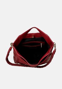 Borsa a tracolla rossa in pelle con tracolla intrecciata, dotata di un ampio interno nero e tasca con zip. Texture trapuntata e finitura liscia.