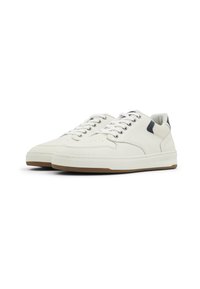 White leather sneakers with a textured finish, round toe, lace-up design, and a rubber sole with a brown accent on the bottom.