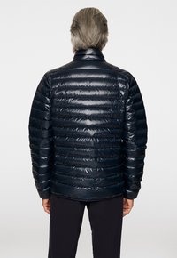 Meripihkava blue quilted puffer jacket, jonka kiiltävä pinta, ominaisuudet, kuten seisova kaulus ja vaakasuorat saumat. Suunniteltu lämpimyyttä ja eristystä varten.