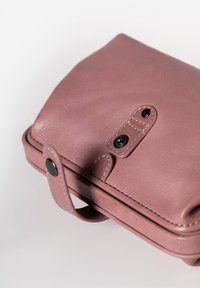 Borsa in pelle rosa con una texture liscia, dotata di chiusura a patta, cuciture a contrasto e manico laterale per un facile trasporto.