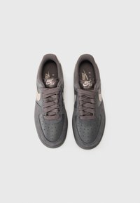 Nike Air Force 1 sneakers in dark gray suede with tonal laces, perforated toe box, and light gray swoosh logo on the sides.