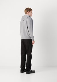 Grijze hoodie met een trekkoord, losse pasvorm, rib gebreide manchetten, gecombineerd met zwarte broeken en zwarte schoenen. Minimalistisch ontwerp en soepele textuur.