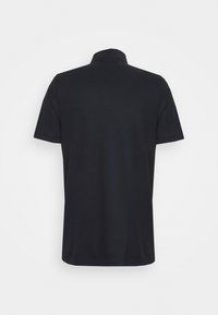 Polo noir à col et manches courtes, en tissu lisse, présentant un design épuré et simple avec un ourlet droit.