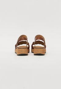 Sandali wedge in pelle marrone con suola in sughero, caratterizzati da un design a strati delle cinghie e una finitura liscia. La vista posteriore mostra un tallone aperto e accenti curvi.