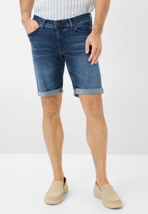 Dai pantaloni corti in denim di colore blu scuro con una vestibilità classica, presentano risvolti, design a cinque tasche e chiusura con zip e bottone.
