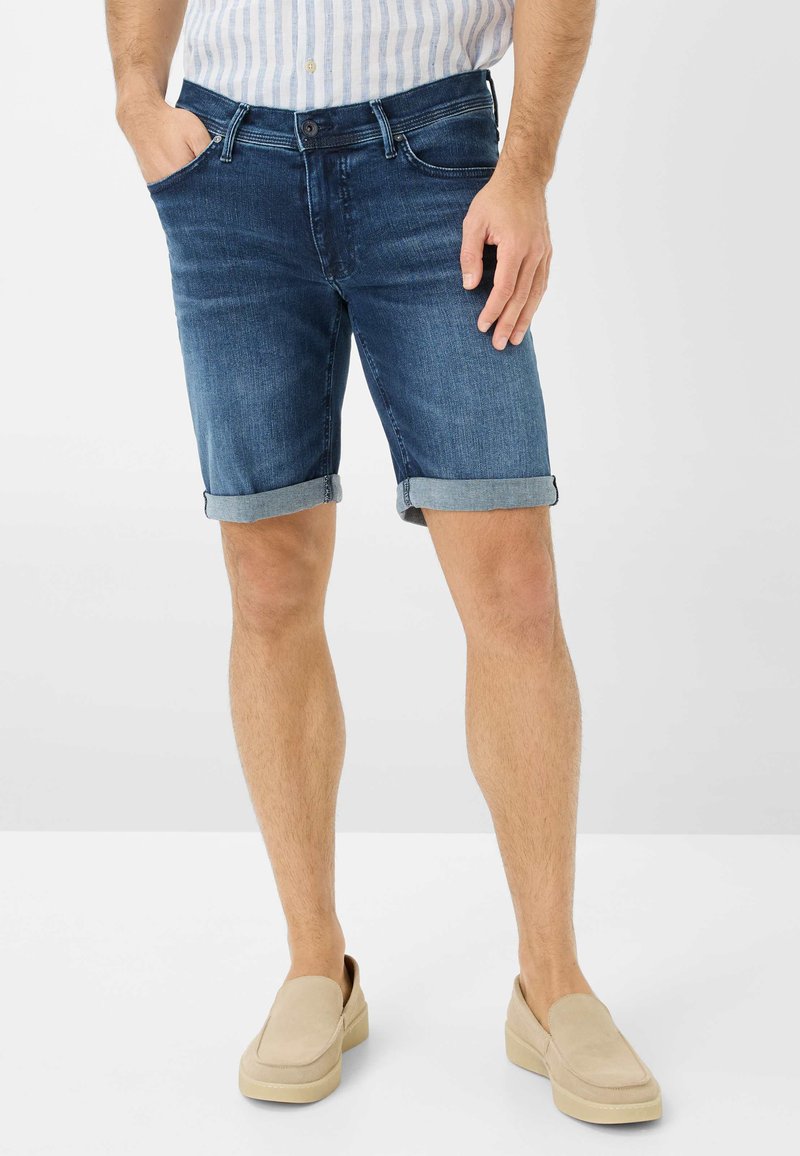 Shorts en denim bleu foncé avec une coupe classique, caractéristiques de revers roulés, design à cinq poches et fermeture à glissière avec bouton.