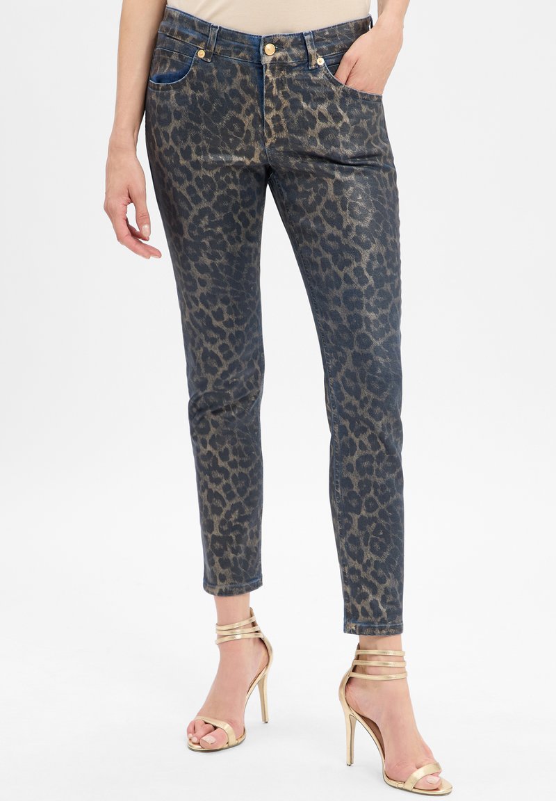 Jeans en denim à imprimé léopard dans des tons bleu foncé et or, présentant une coupe slim, un design à cinq poches et des accents en métal doré.