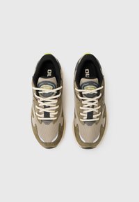 Beige and olive green athletic shoes with mesh and suede materials, featuring beige laces, black accents, and a textured sole.