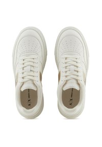 Zapatillas de cuero blanco con caja de puntera perforada, detalles en beige en los laterales y cordones planos. Cuentan con suelas acolchadas y un detalle del logo en el interior.