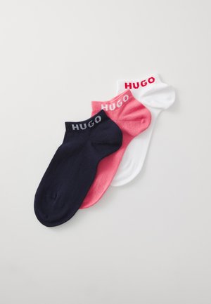Trois paires de chaussettes de cheville en marine, rose et blanc, avec le nom de la marque "HUGO" tricoté en couleurs contrastées sur les bordures.