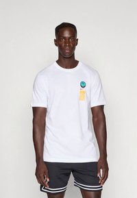 Hvit bomulls-t-skjorte med en turkis basketballgrafikk og oransje kurvdesign på venstre bryst. Rund hals, korte ermer.