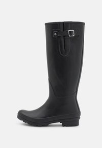 Botte noire en caoutchouc jusqu'au genou avec un bout rond et une semelle texturée. Présente une sangle décorative et un accent en boucle argentée sur le dessus.