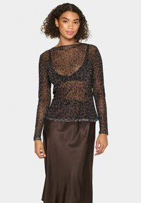 Črna leopardja vzorčasta dolgosleeve prosojna bluza z okroglim izrezom in oprijetim krojem, položena čez satensko rjavo krilo.