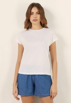 Witte T-shirt met korte mouwen, gemaakt van lichtgewicht stof, met een ronde halslijn en een ontspannen pasvorm. Gecombineerd met denim korte broek.
