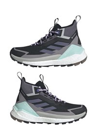 Chaussures de randonnée montantes noires et grises avec des lacets violet clair, des semelles blanches, des accents vert menthe au talon et des étiquettes de marque Terrex et Gore-Tex.