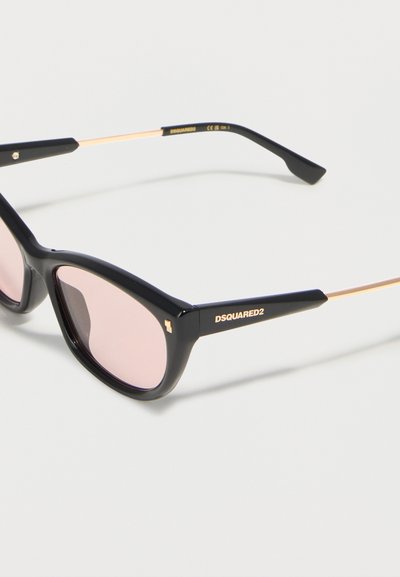 Μαύρα οβάλ γυαλιά ηλίου με φακούς ροζ απόχρωσης και χρυσές λεπτομέρειες, επωνυμία DSQUARED2 στο μπράτσο του σκελετού.
