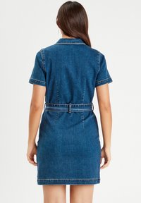 Abito di jeans con maniche corte, collo a camicia, vita cin cin centrata da una cintura, di colore blu scuro con cuciture in contrasto lungo le cuciture.