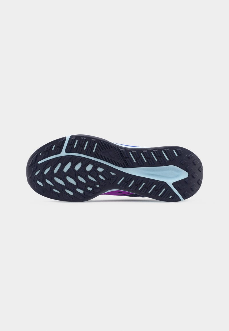Suela de zapato deportivo negro y azul claro con agarre texturizado y ranuras, vista desde abajo sobre un fondo blanco.