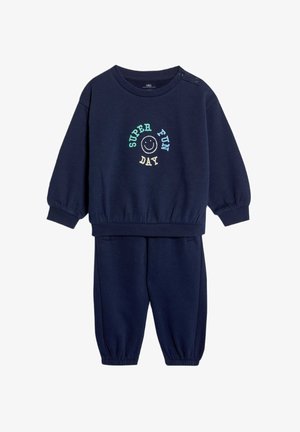 Conjunto de sudadera y pantalones deportivos en azul marino, con cuello redondo, puños acanalados y el bordado "DÍA SUPER DIVERTIDO" acompañado de una carita sonriente. Textura de tela suave.