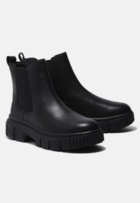 Black leather ankle boots with elastic side panels, chunky rubber soles, and pull tabs at the back. Smooth texture and minimal design.