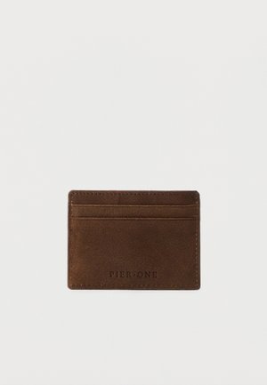 Suport pentru carduri din piele maro, cu trei sloturi pentru carduri și inscripția „Pier One” embosată pe față, prezentat pe un fundal alb.