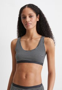 Svartvit randig bralette med breda axelband och rundad halsringning. Bandet har präglad logotyp. Mjuk, elastisk material.