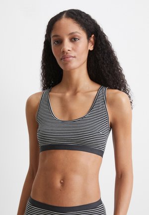 Bralette a righe bianche e nere con spalline larghe e scollatura arrotondata. La fascia presenta un marchio in rilievo. Materiale morbido e elasticizzato.