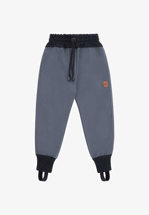 Szare spodnie dresowe dla dzieci z czarnym elastycznym pasem, sznurkiem do wiązania, ściągaczami przy nogawkach oraz paskami na stopy, z małą brązową łatką na nogawce.