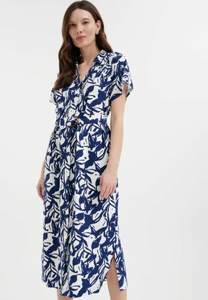 Vestido azul marino y blanco con mangas cortas, cierre de botones, patrón floral, cintura ceñida con cinta y aberturas laterales para mayor comodidad al moverse.