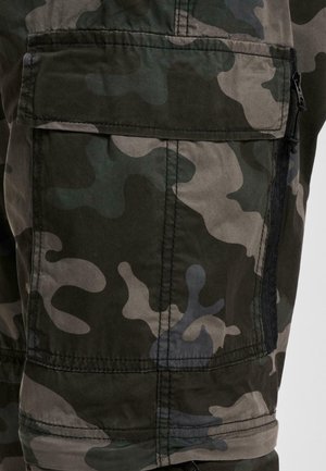 Acercamiento de un bolsillo de pantalones cargo de camuflaje en verde oscuro y gris, con solapa y detalle de cremallera negra en el lateral.
