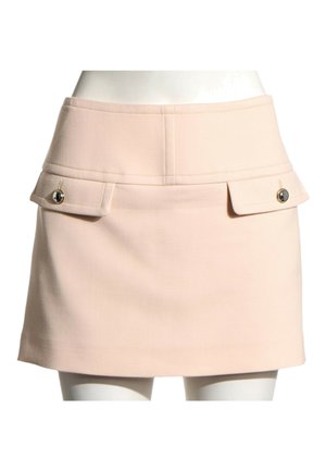Mini-jupe beige à taille haute avec deux poches à rabat ornées de boutons dorés à l'avant, portée sur un buste de mannequin.