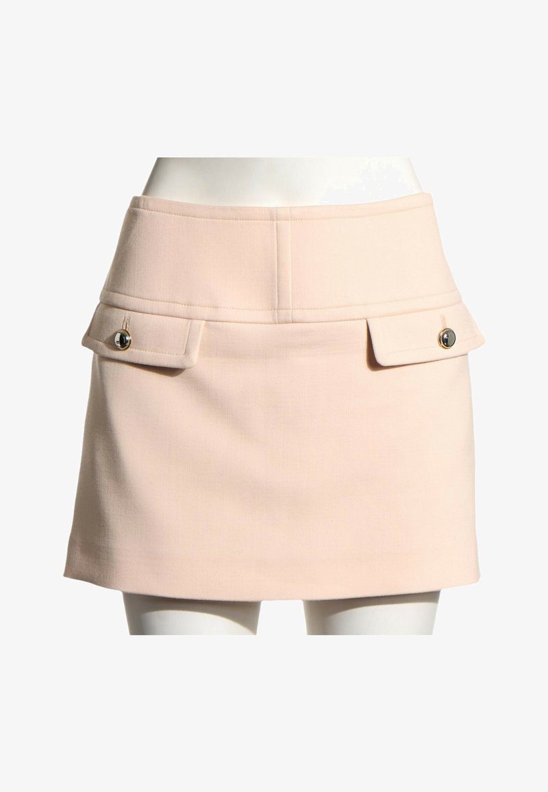 Mini-jupe beige à taille haute avec deux poches à rabat ornées de boutons dorés à l'avant, portée sur un buste de mannequin.