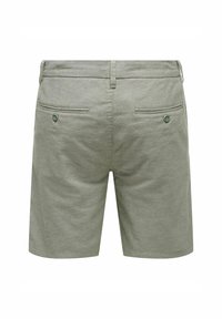 Shorts en coton verts au design simple, dotés de deux poches arrière, chacune avec un bouton, et d'une coupe droite. Texture mate.