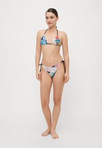 Bikini triangle en tissu multicolore avec des motifs floraux, doté de liens noirs et de fines bretelles, conçu pour une silhouette ajustée.