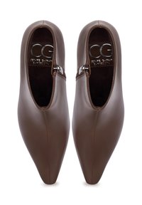 Bruine leren schoenen met een puntige neus, voorzien van een zijrits en een gladde afwerking, in contrast met een binnenvoering van textuur.