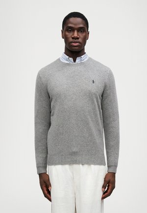 Pull en laine gris avec un col rond, des poignets et un ourlet côtelés, associé à une chemise à col vichy bleue et blanche en dessous.