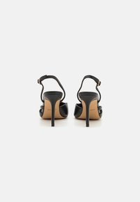 Black high-heeled sandals with a sleek design, open back, thin ankle strap, and a smooth leather finish on a light-colored sole.