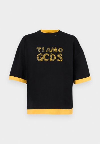 Schwarzes übergroßes T-Shirt mit gelbem Kragen, Ärmelsäumen, Saum und gemustertem Text "TI AMO GCDS" in Gelb auf der Vorderseite in der Mitte.