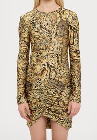 Långärmad klänning i guld med leopardmönster. Rynkade detaljer vid midjan och i fållen skapar en figurnära silhuett.