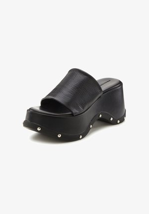 Black platform slide sandals with a textured leather strap, curved sole, and metallic studs along the outer edge. Smooth finish on footbed.