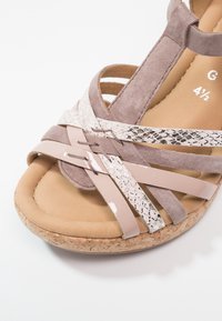 Sandale pour femme avec des brides à textures multiples en mauve, imprimé serpent et cuir verni sur une semelle en liège et une semelle intérieure rembourrée beige.