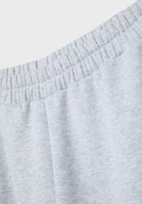 Nahaufnahme von hellgrauem Stoff mit elastischem Bund, der eine weiche Textur und gesammelte Nahtdetails zeigt.