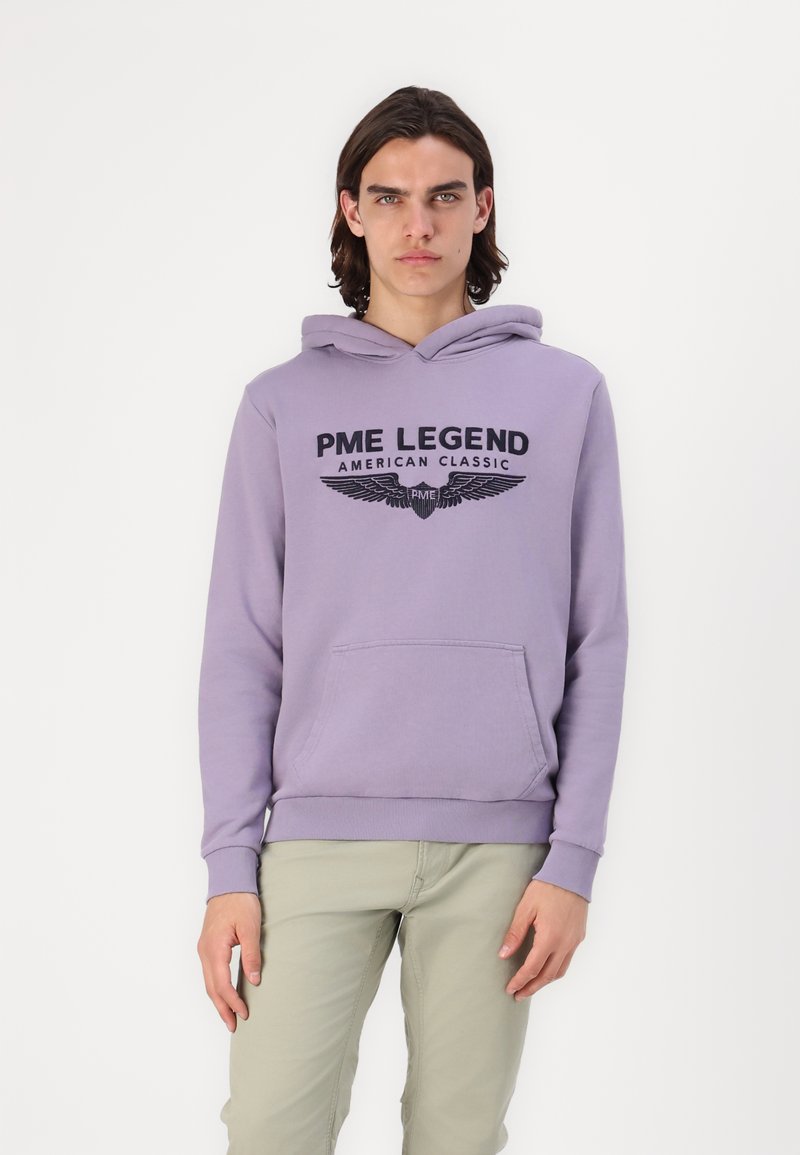 Fialová mikina s predným klokaním vreckom, s nápisom "PME LEGEND AMERICAN CLASSIC" a grafikou krídiel. Mäkká tkanina a rebrované manžety.