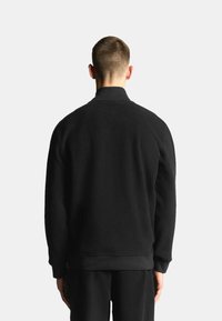 Schwarze Fleecejacke mit hohem Kragen, langen Ärmeln und lockerem Schnitt. Verfügt über eine weiche Textur mit gerippten Bündchen und Saum.