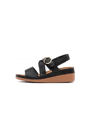 Sandalia negra de cuero con dos tiras anchas, una hebilla dorada y una suela cuña color marrón claro sobre un fondo blanco.