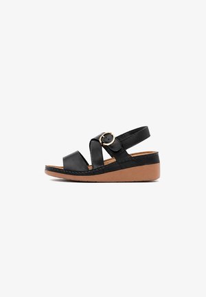 Sandalia negra de cuero con dos tiras anchas, una hebilla dorada y una suela cuña color marrón claro sobre un fondo blanco.