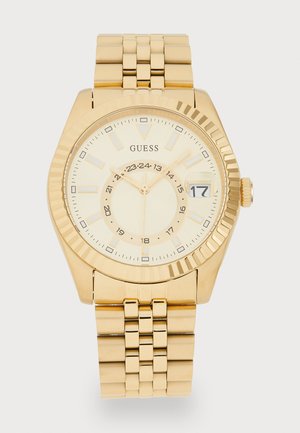 Montre en acier inoxydable doré avec un boîtier rond, une lunette texturée et un cadran doré clair. Comprend des index horaires et un affichage de la date.