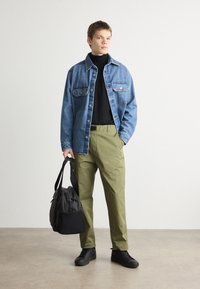 Jeans jakna, črn pulover z visokim ovratnikom, olivno zeleni hlačni. Črna torba z nastavljivim trakom. Črne superge. Gladke teksture, sproščen kroj.