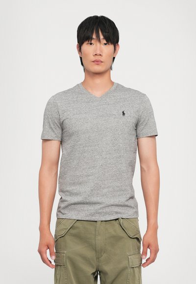 Szara krótki rękaw T-shirt z dekoltem w kształcie V, uszyty z miękkiego, teksturowanego materiału, z małym czarnym logo na lewej piersi, w połączeniu z zielonymi szortami cargo.