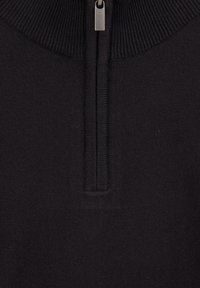 Tuvumā melna adīta auduma ar vertikālu sudraba rāvējslēdzēju un ribota apkakles detaļu.